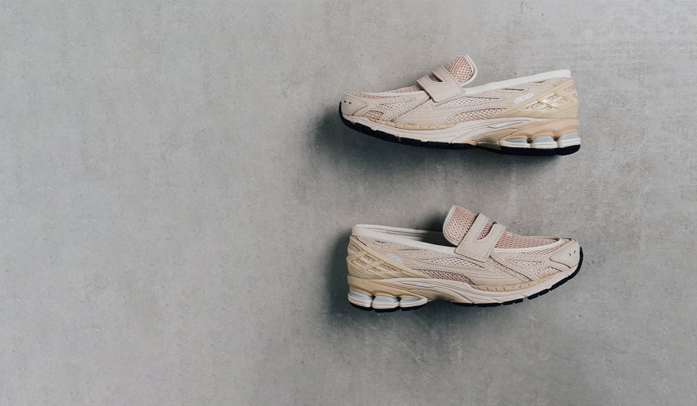 Side view of a pair of beige NB 1906L loafers with mesh and suede upper, Velcro straps, and sporty sole, placed against a concrete background.