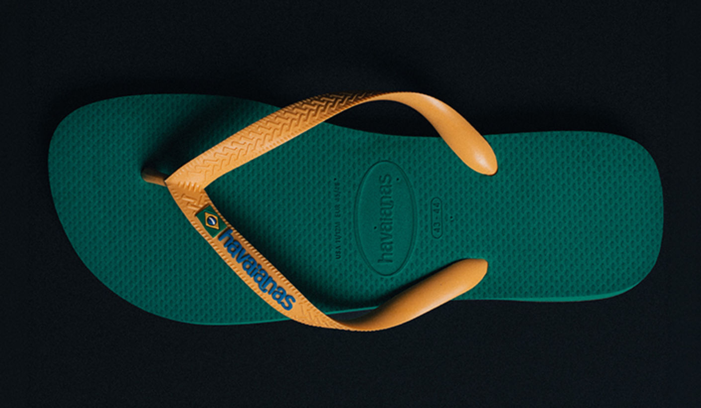 Green Havaianas flip-flop with yellow straps and logo detail, photographed from above on a dark background.