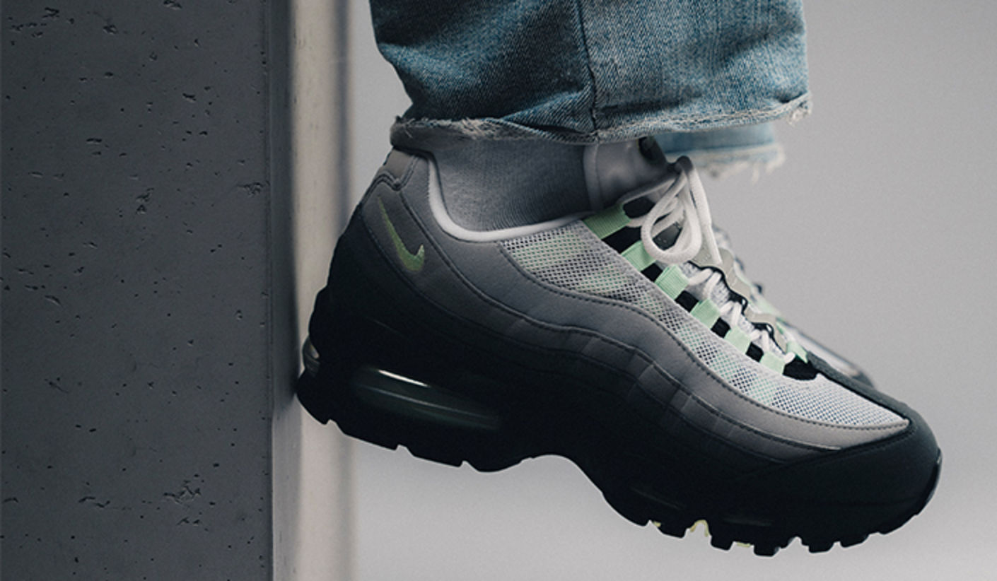 Nike Air Max 95 OG “Big Bubble Fresh Mint” sneaker in grey with mint accents, shown on foot against a minimal concrete wall.