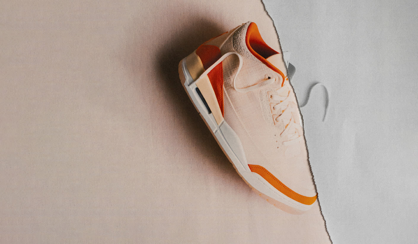 Air Jordan 3 in beige with bold orange details, shown on a torn beige and grey paper background.
