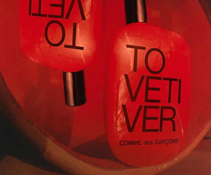 Comme des Garçons To Vetiver perfume bottles in red with bold black lettering.