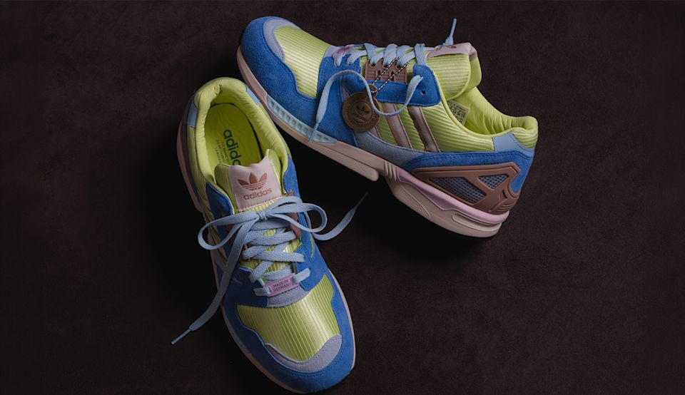 Adidas ZX8000 sneakers in blue suede and neon yellow mesh with pastel pink details, displayed on a dark textured surface.