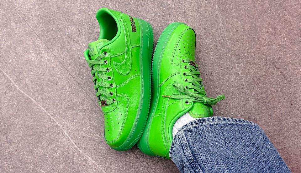 Nike Air Force 1 Low LX “Icon” in bright green leather with tonal Swoosh and laces, worn with blue denim jeans on a gray floor.