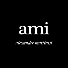 Logo of the brand "ami" in white lowercase letters with "alexandre mattiussi" in cursive below, on a black background.