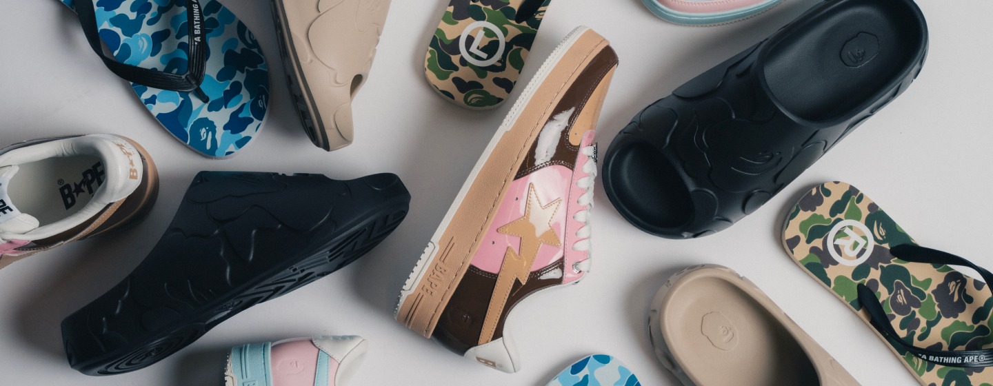 A selection of BAPE footwear including sneakers, slides, and flip-flops arranged on a light background, featuring signature camouflage patterns and bold streetwear-inspired designs.