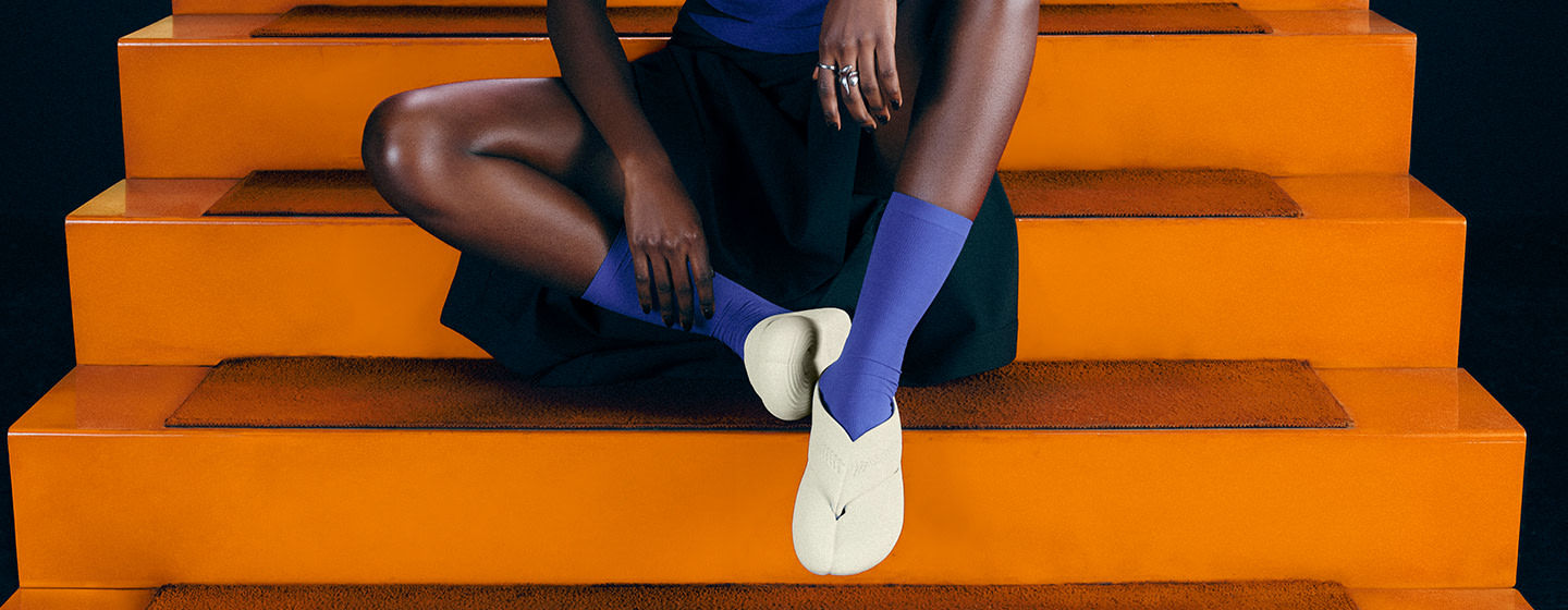 Havaianas x Zellerfeld footwear styled with purple socks and a black-and-purple outfit on bright orange steps.
