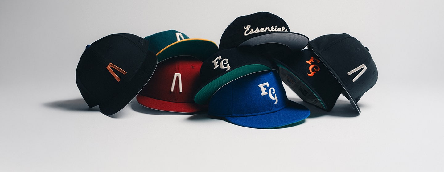 Assortment of six colorful flat-brim caps with embroidered logos, stacked together on a light background, including black, red, blue, and green designs.