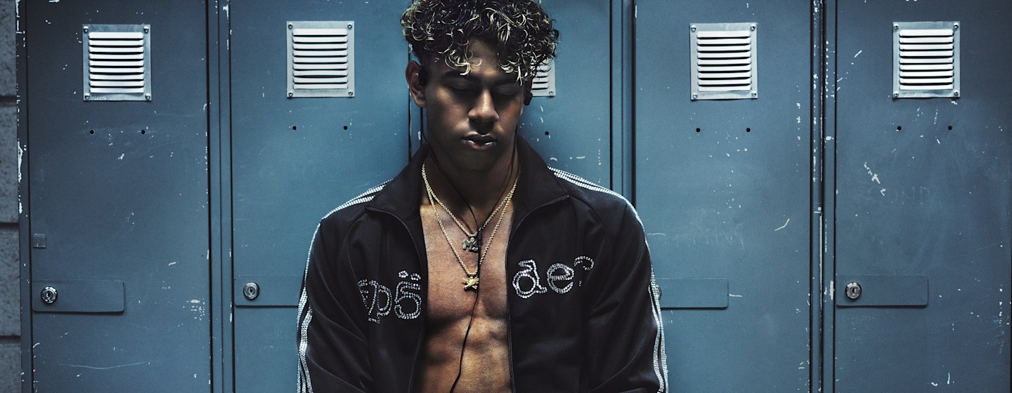 Lamine Yamal wearing a black adidas x Sp5der jersey, looking directly at the camera in an industrial setting.