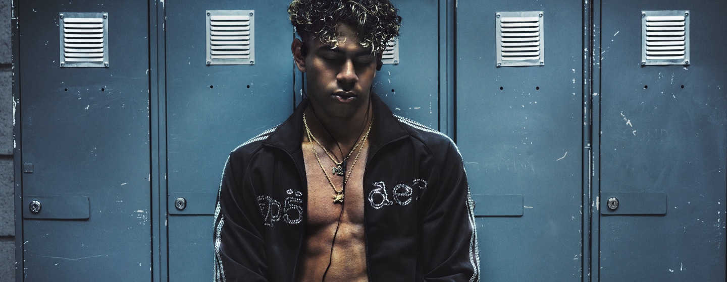 Lamine Yamal wearing a black adidas x Sp5der jersey, looking directly at the camera in an industrial setting.