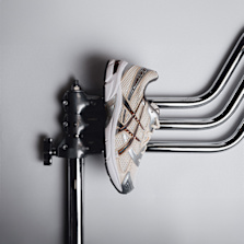 A silver and beige ASICS GEL-1130 sneaker photographed on a minimalist light gray surface.
