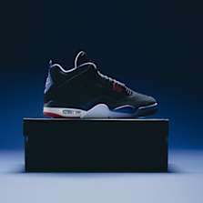 A single Air Jordan 4 sneaker in a black and red colorway displayed on top of a black shoebox with a dark blue background.