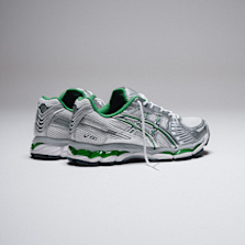 Pair of ASICS running shoes in silver with green accents, positioned on a neutral background.