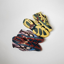 Three pairs of ASICS GEL DS Trainer 14 sneakers in bold colorways—yellow/black, red/black, and blue/black—stacked diagonally with soles visible.