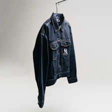 "Dark blue denim jacket with a New York Yankees logo on the chest, hanging on a hook against a light background."