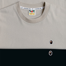 "Two folded A Bathing Ape T-shirts in beige and black, featuring a small embroidered ape logo on the chest."