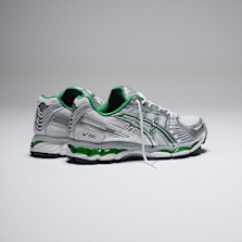 Pair of ASICS running shoes in silver with green accents, positioned on a neutral background.