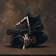 Air Jordan 3 "Fireside" in black textured leather, styled in a stacked product shot against a warm brown studio backdrop.