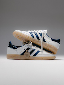 “Pair of adidas Spezial sneakers in white with navy stripes and gum sole, stacked together against a light grey background.”