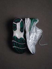 “Pair of ASICS GEL-Kayano sneakers in silver and green, shown from side and sole view on a dark background.”