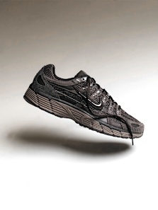 Black and brown Nike sneaker with mesh detailing floating against a neutral gradient background, highlighting its lightweight and breathable design.