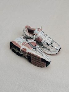 A pair of white and rose gold Nike Vomero sneakers with silver accents, shown on a light background.