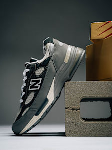 New Balance 992 grey sneaker with mesh and suede panels, styled on a concrete block next to a shoebox in a minimal studio setup.