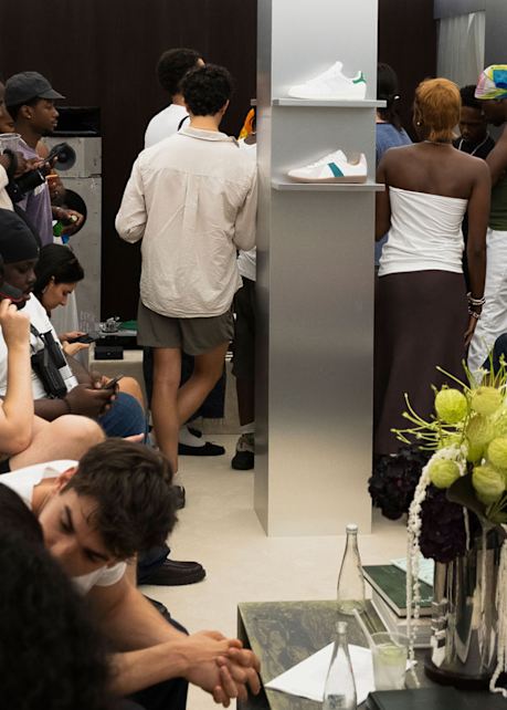 Guests gathered at a Stan Smith event, with adidas Stan Smith sneakers displayed on shelves in a modern showroom setting.